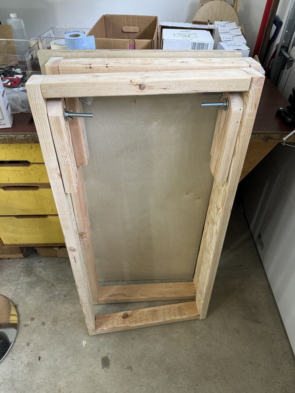 Underside of a wooden cornhole board showing its frame, legs, and hardware.
