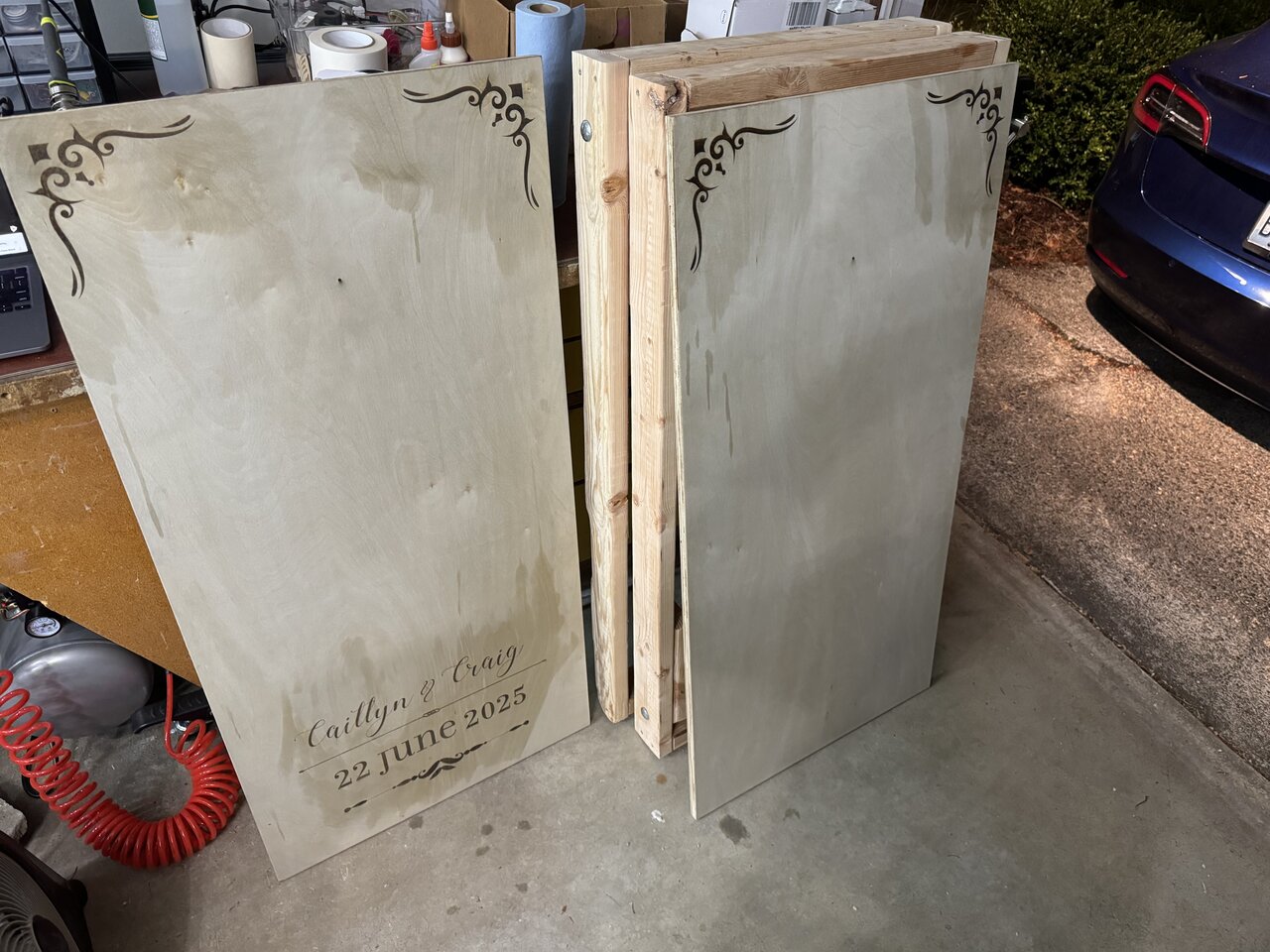 Two engraved cornhole board panels side by side in the workshop.