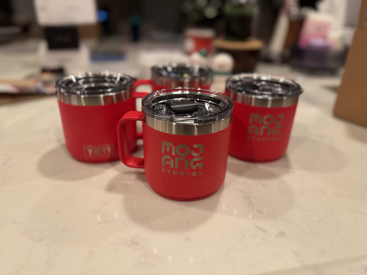 Red insulated mugs engraved with the Mojang Studios logo.
