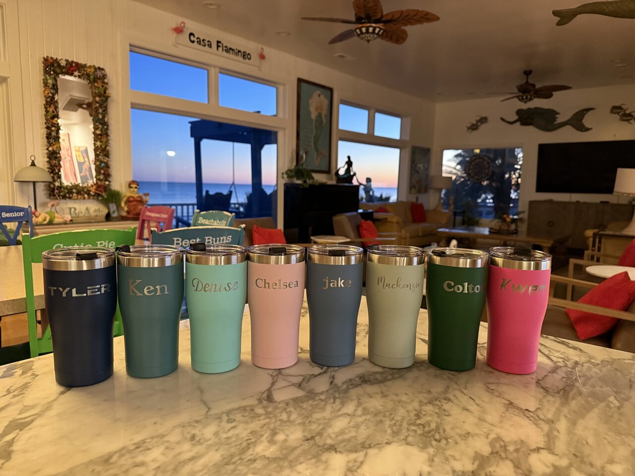 A row of colorful tumblers, each engraved with a different name.